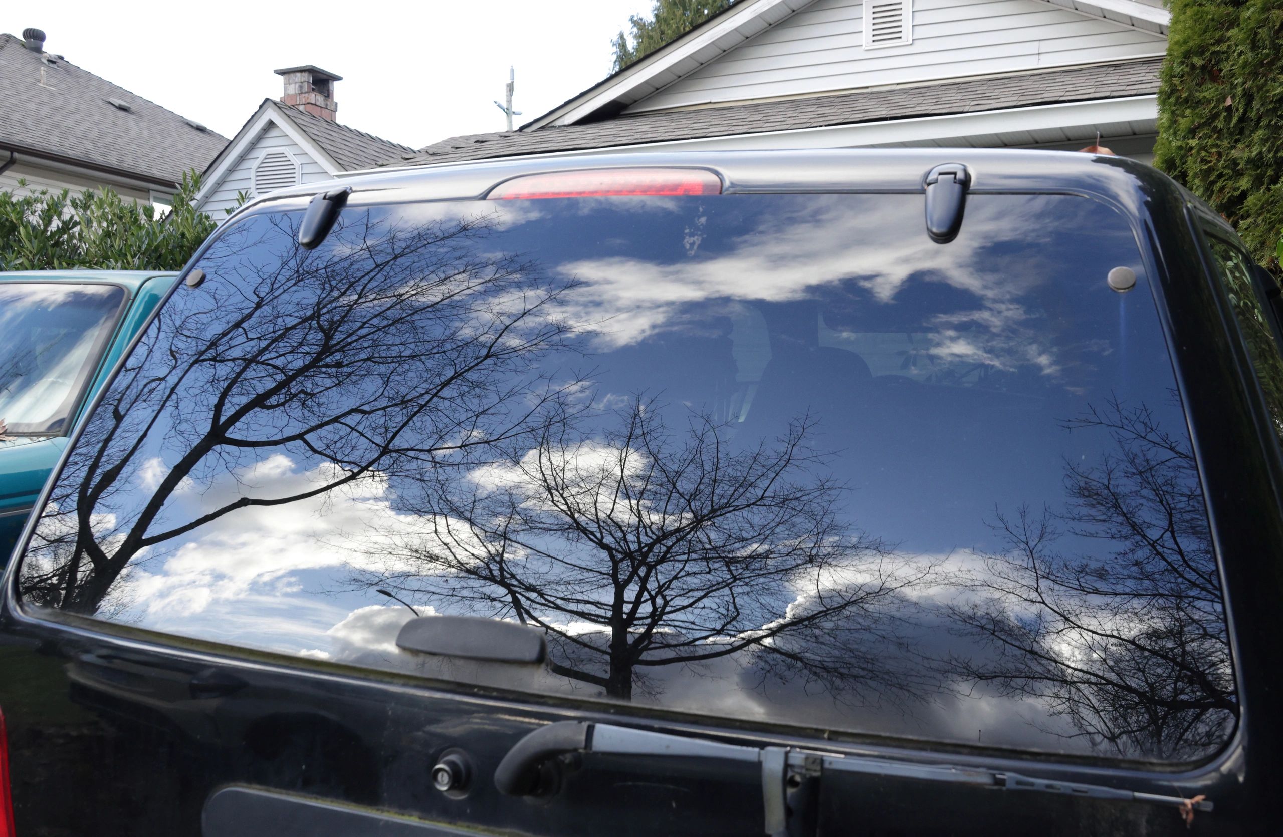 Car window reflections of trees and clouds