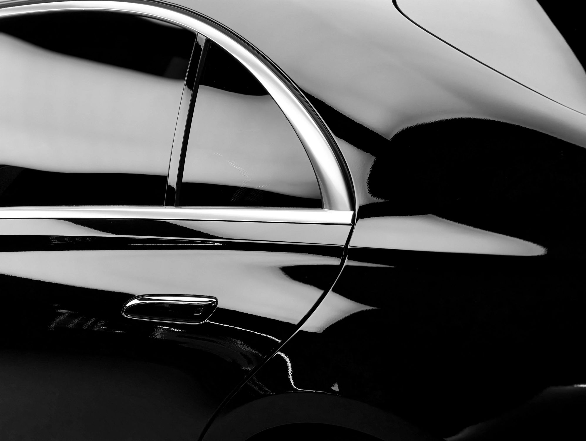 Close-up of glossy black car body and chrome trim